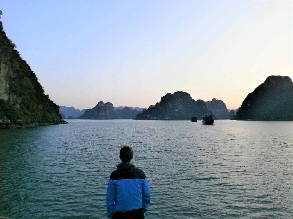 Sunrise over Halong Bay, with rock formations illuminated by the rising sun.