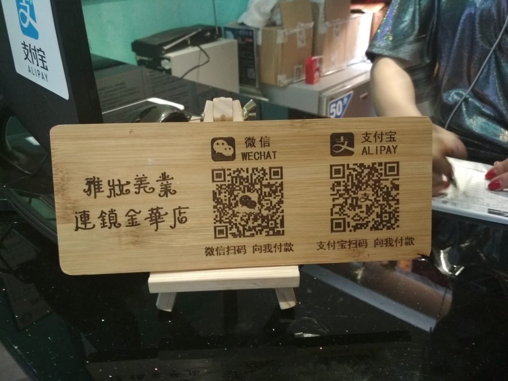 Letrero con código para realizar pagos en China, destacando opciones como WeChat y Alipay