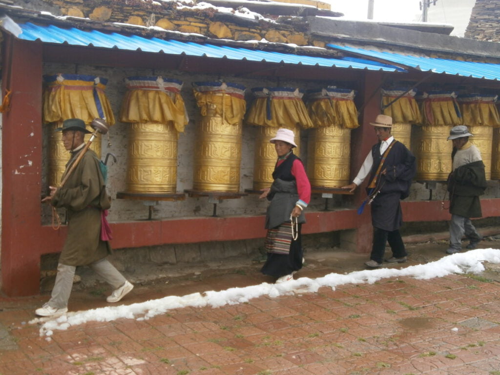 Tibetan people praying by prayer wheels in Litang, Sichuan.