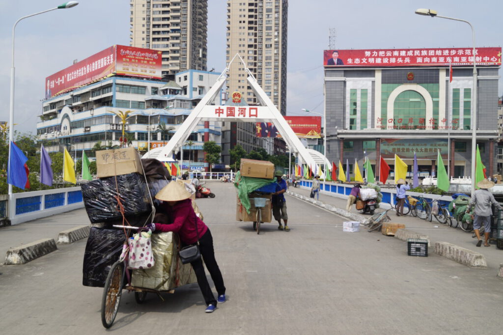 Personas arrastrando bicicletas con cajas en el Puente entre Hekou y Lao Cai